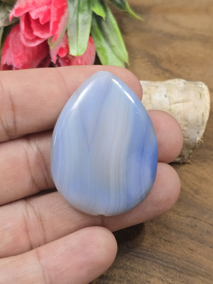 Polierter blauer Achat-Pendant in Tropfenform auf der flachen Hand als Größenvergleich für DIY-Schmuck.