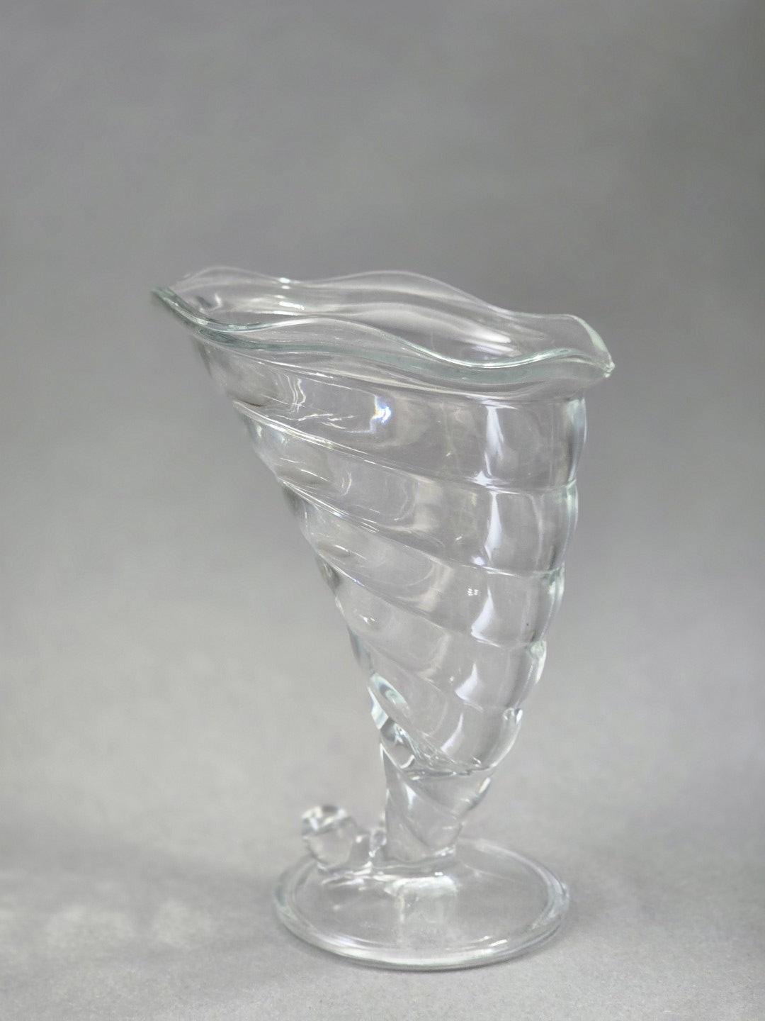 Ein einzelner transparenter Fortuna Eisbecher ist seitlich zu sehen, mit kelchförmiger Schale, spiralförmigem Pressglasdekor und welligem Rand.