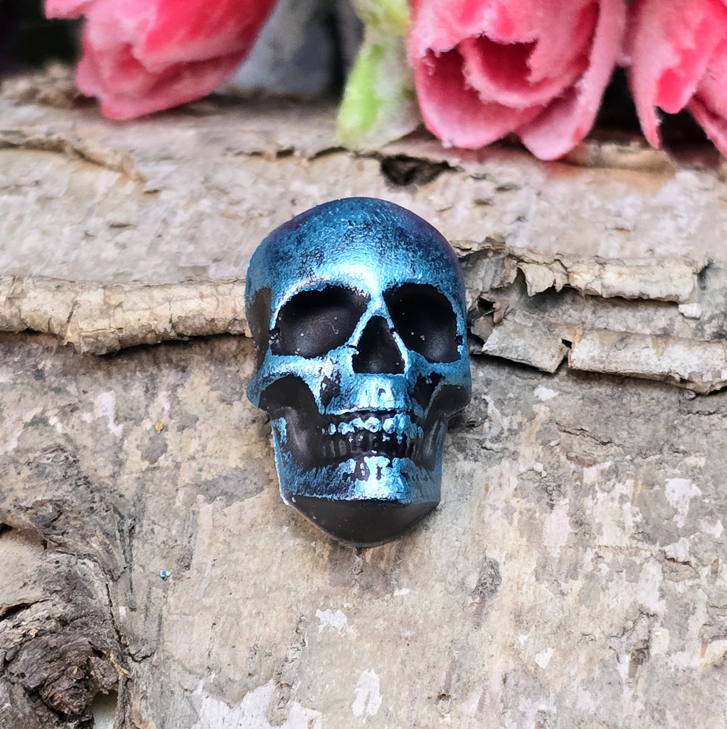 Das Bild zeigt einen Totenkopf-Cabochon in Schwarz mit türkisfarbener Wachsverzierung