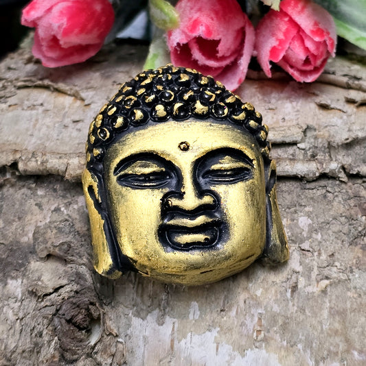 Auf dem Bild  ist ein handgefertigter Buddhakopf aus Kunstharz zu sehen. Der Kopf ist mit feinen, handbemalten Details verziert und hat eine flache Rückseite, die ideal für  die Schmuckherstellung oder Bastelprojekte geeignet ist.