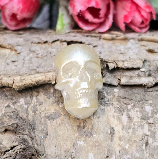Das Bild zeigt einen Cabochon aus Resin mit cremeweißer Farbe auf einem Stück Birke.