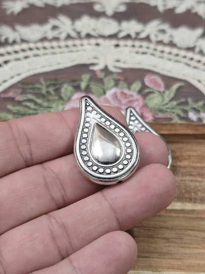 Tropfenförmige CCB Perle in Altsilber mit Zierrand an der Hand gehalten als Größenvergleich für Ketten und Armbänder.
