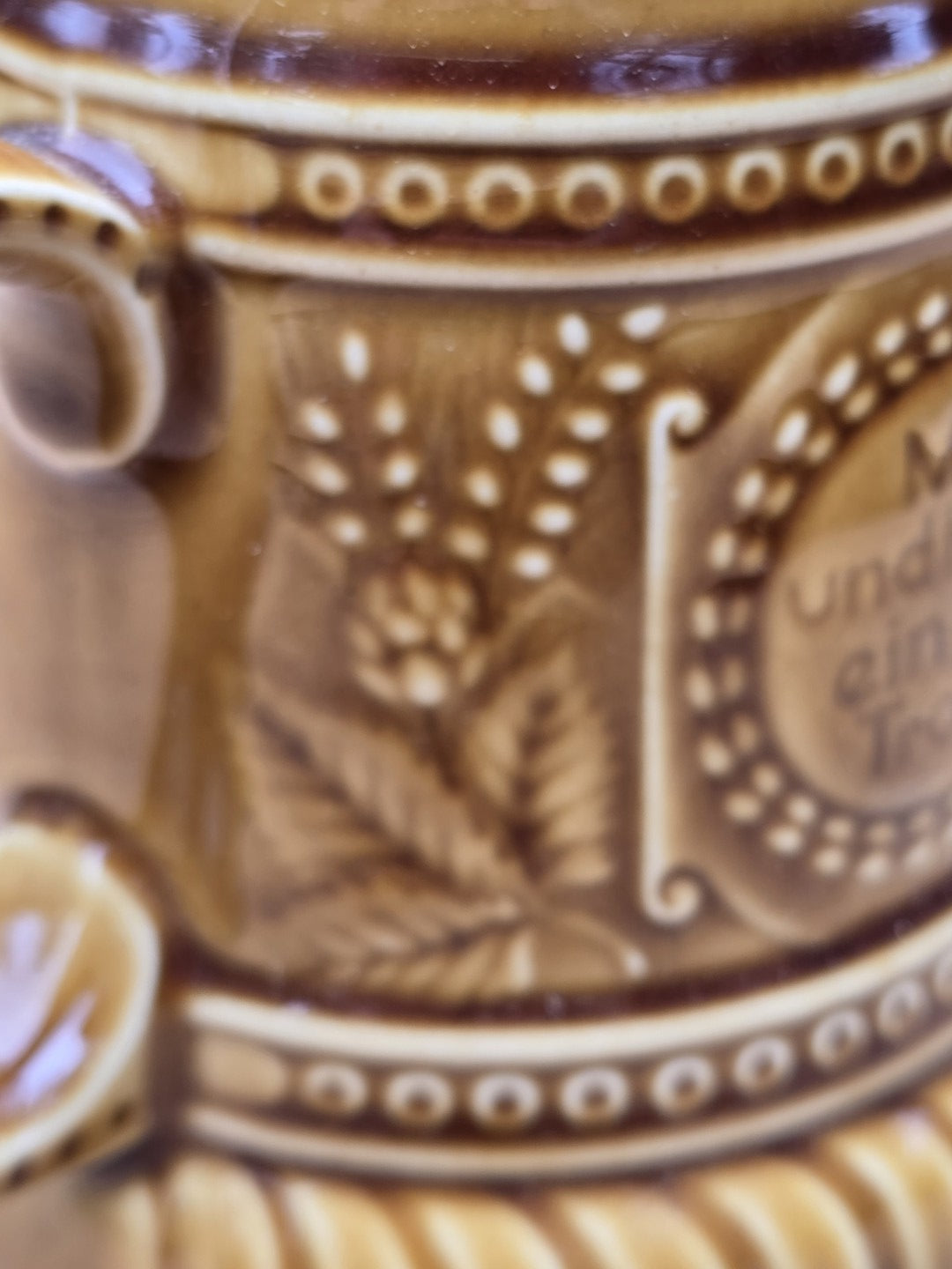 Florales Reliefdekor mit Hopfenmotiv und Punktmuster auf braunem Vintage Bierkrug