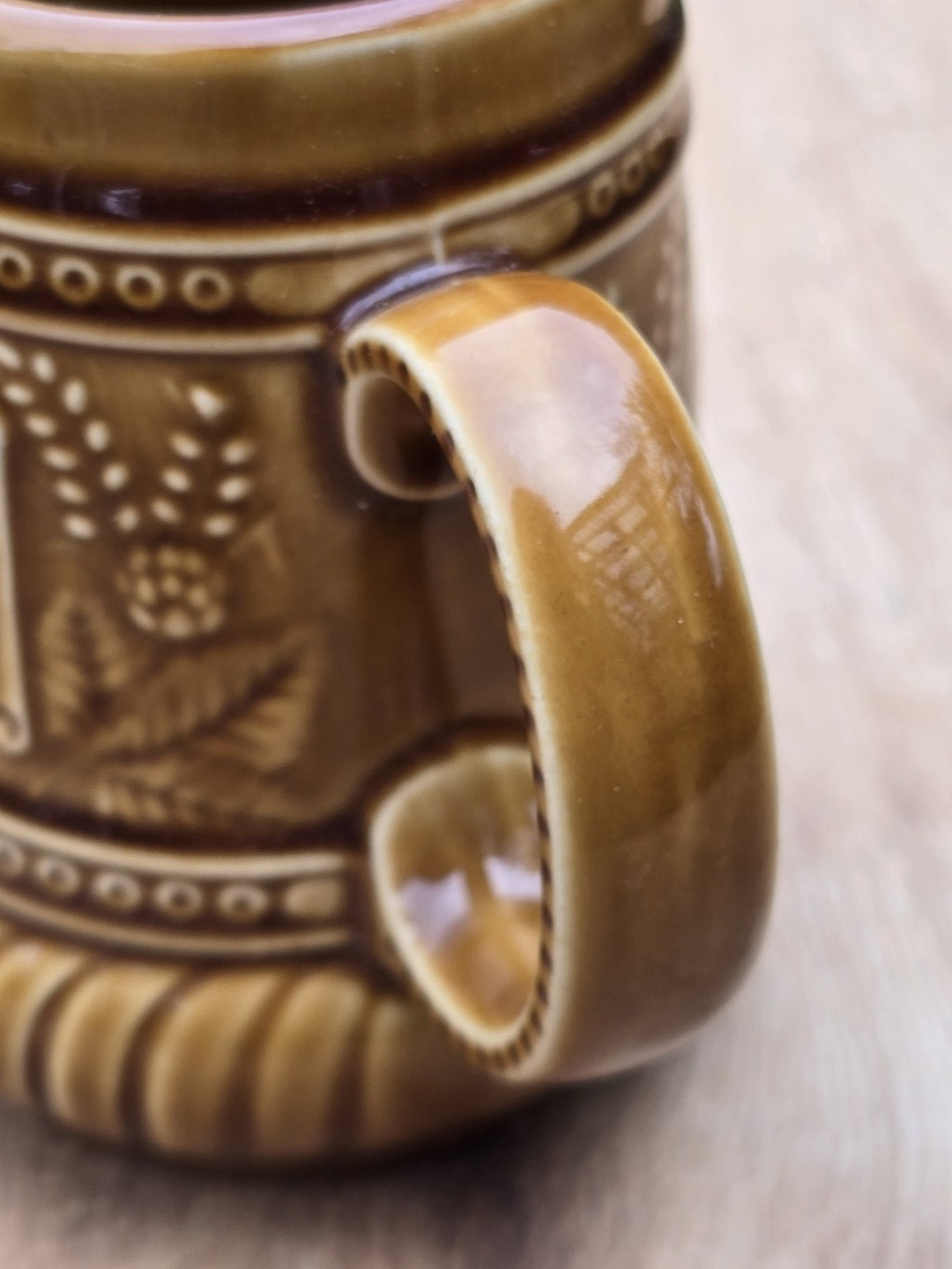Nahaufnahme des Henkels und Hopfendekors an einem braunen Vintage Keramik Bierseidel