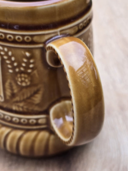 Nahaufnahme des Henkels und Hopfendekors an einem braunen Vintage Keramik Bierseidel