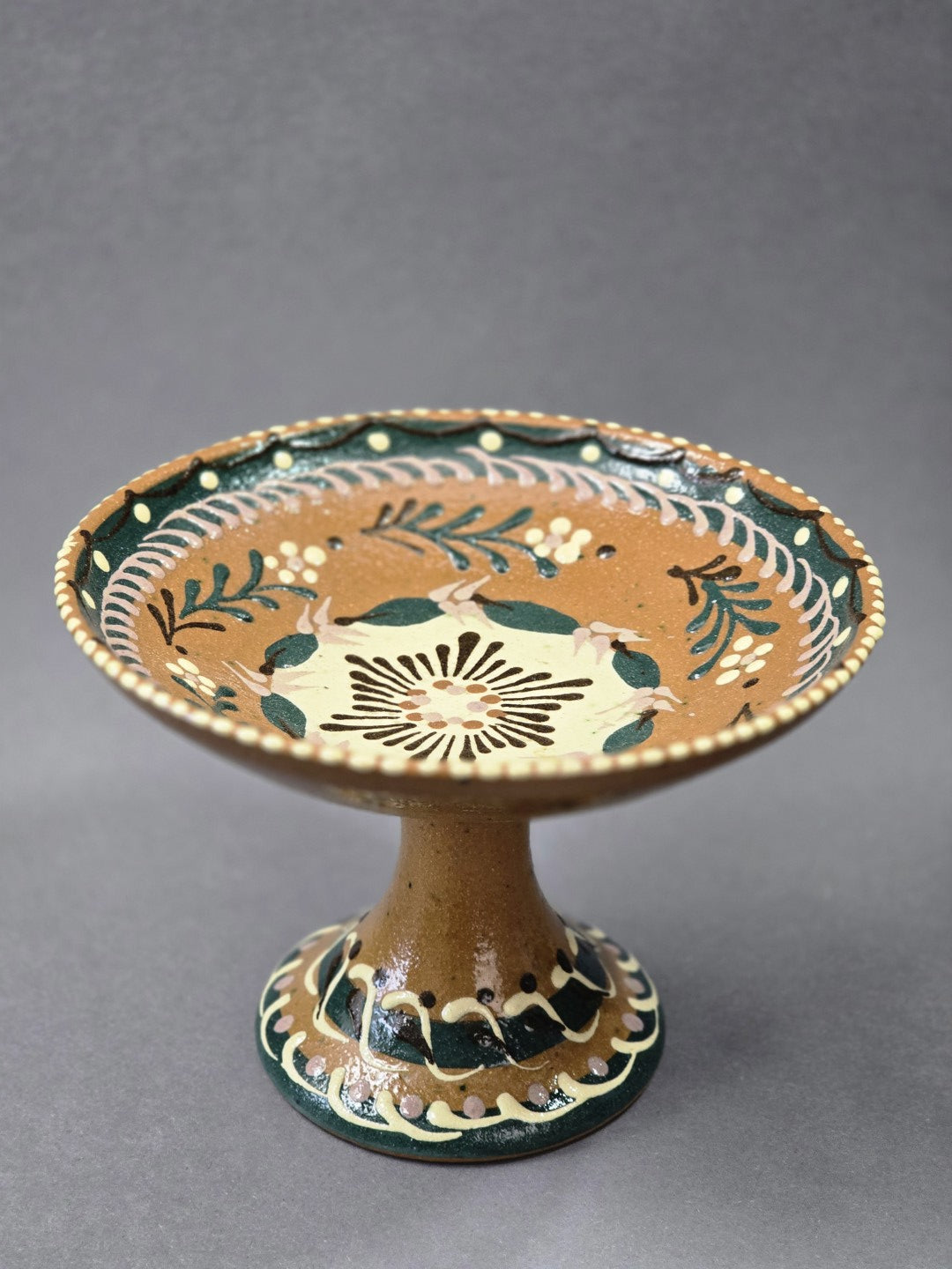Vintage Keramik-Fußschale mit brauner Glasur und floralem Dekor in Dunkelgrün, Creme und Rosa, schräg von vorn fotografiert