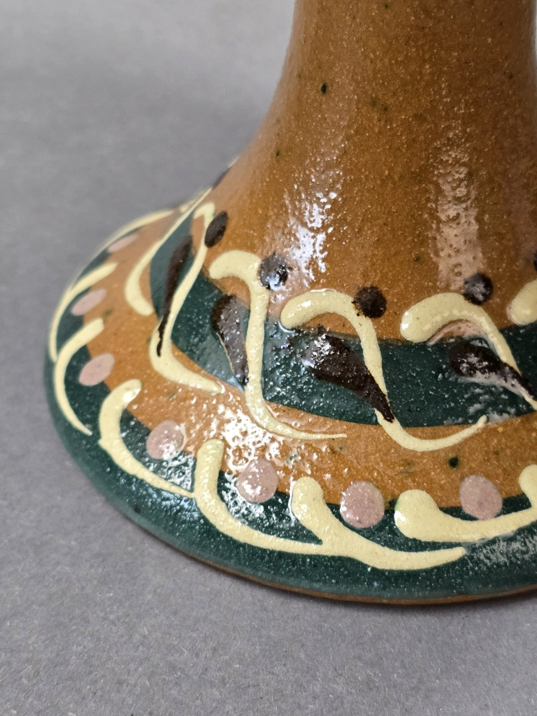 Vintage Keramik-Fußschale mit braun glasiertem Standfuß und ornamentaler Bemalung in Grün, Creme und Rosa in Nahaufnahme