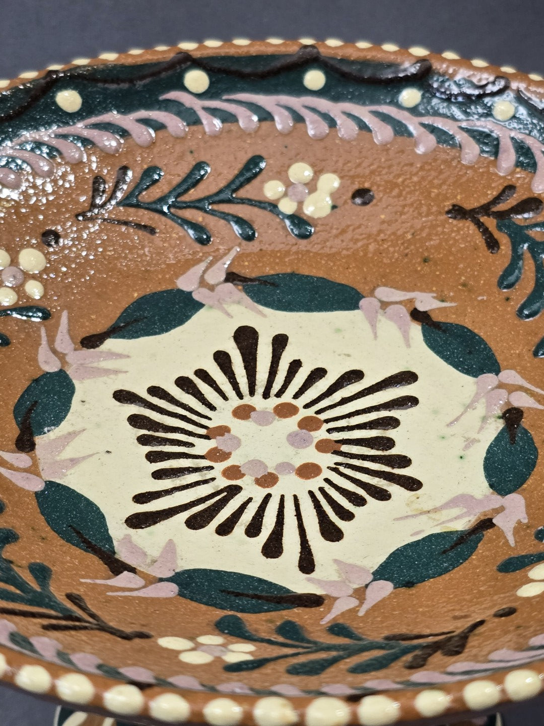 Vintage Keramik-Fußschale mit großem cremefarbenem Blütenmotiv, grünen Blättern und rosa Akzenten in Nahaufnahme der Schalenmitte