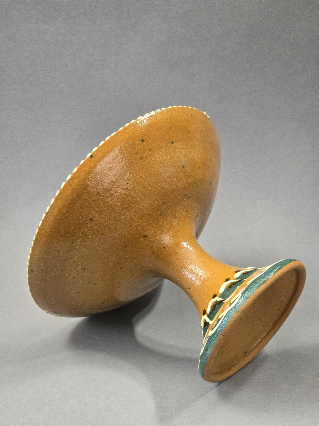 Vintage Keramik-Fußschale in Unteransicht mit brauner Keramikoberfläche, hohem Fuß und bemaltem Standring, seitlich liegend fotografiert