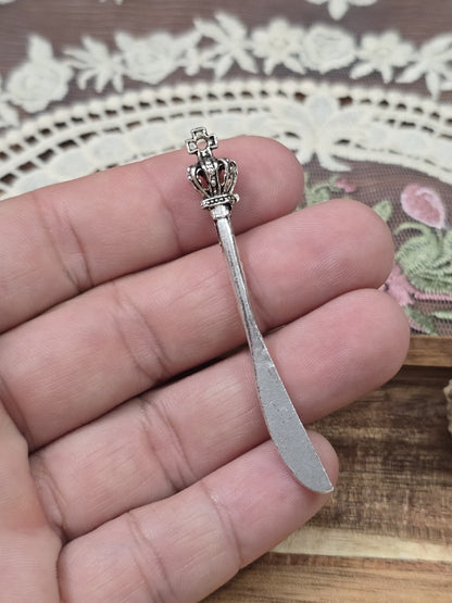 Langer Messer-Charm 60mm in Silber-Optik mit Kronen-Griff auf einer Hand gehalten als Größenvergleich.