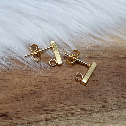 Das Bild zeigt goldfarbige Ohrstecker aus Edelstahl in Stäbchenform mit Öse & Flügelmuttern.