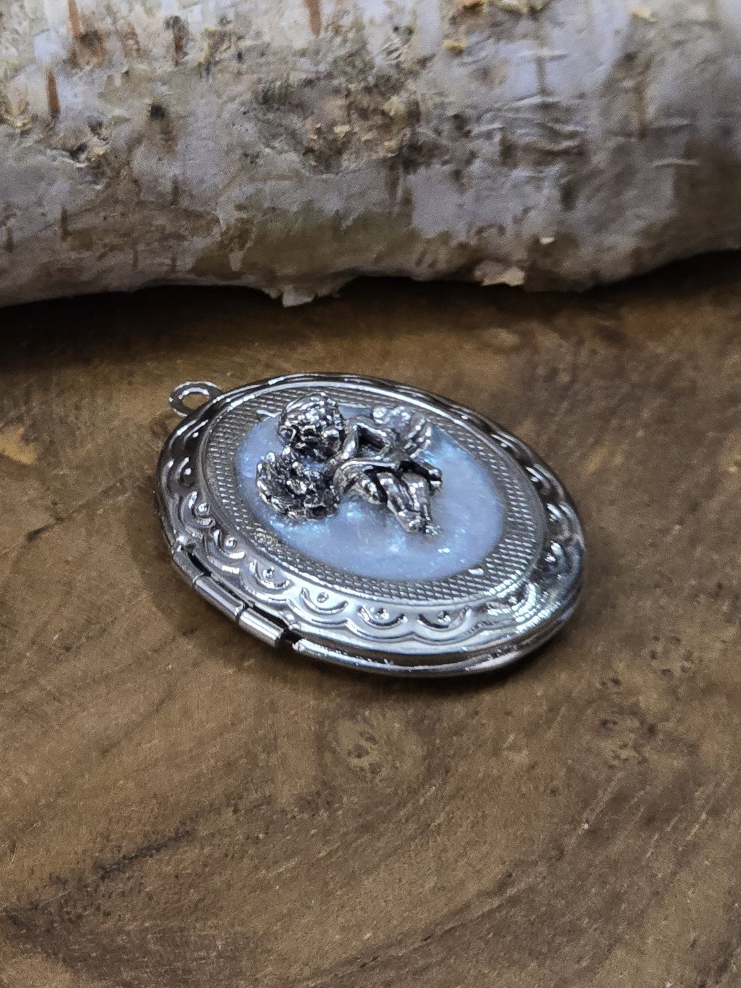 Detailaufnahme eines Engel-Medaillons mit glänzender Oberfläche und dekorativem Metallrand
