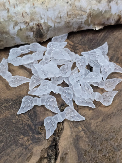 Gefrostete weiße Engelsflügel-Perlen aus Acryl auf Rustikalholz zur Schmuckherstellung.