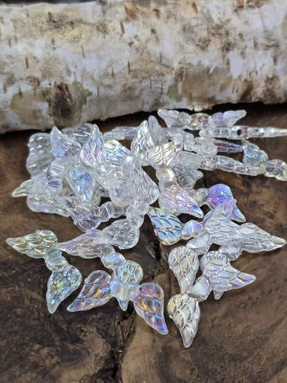 Transparente Engelsflügel-Perlen mit Regenbogen-Schimmer (AB-Effekt) auf Holzuntergrund.