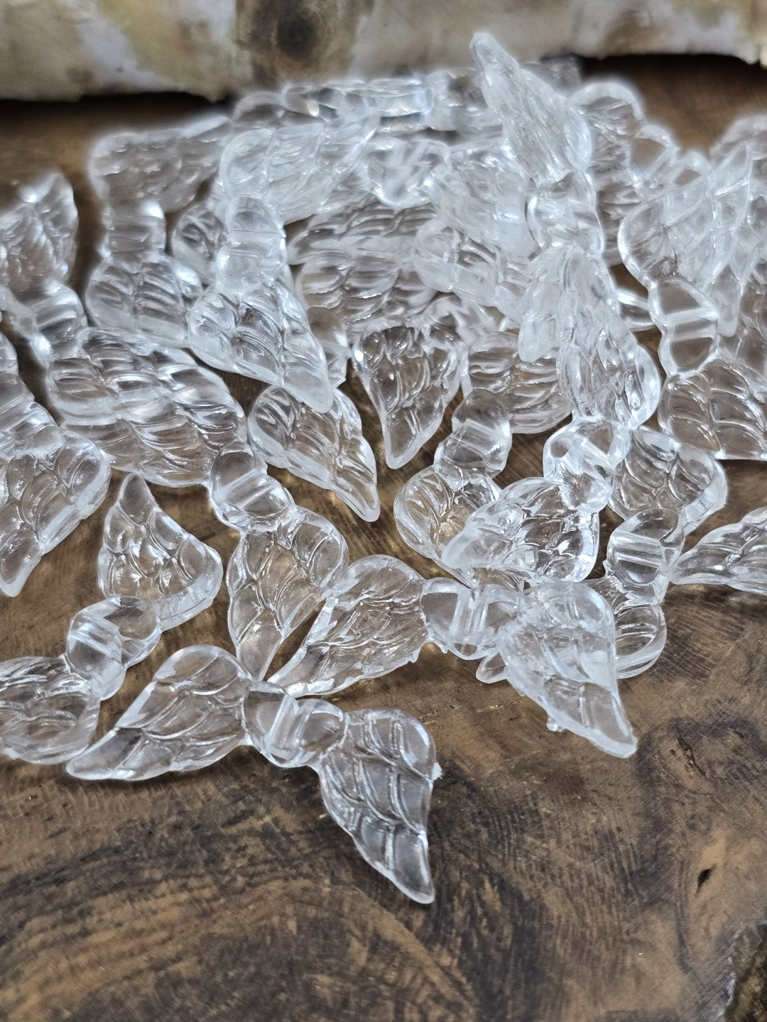 Klar transparente Engelsflügel-Perlen aus Acryl mit detaillierter Federprägung in der Nahaufnahme.