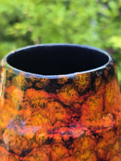 Detail der schmalen Öffnung einer roten orangefarbenen Keramikvase mit dunklem Innenrand.