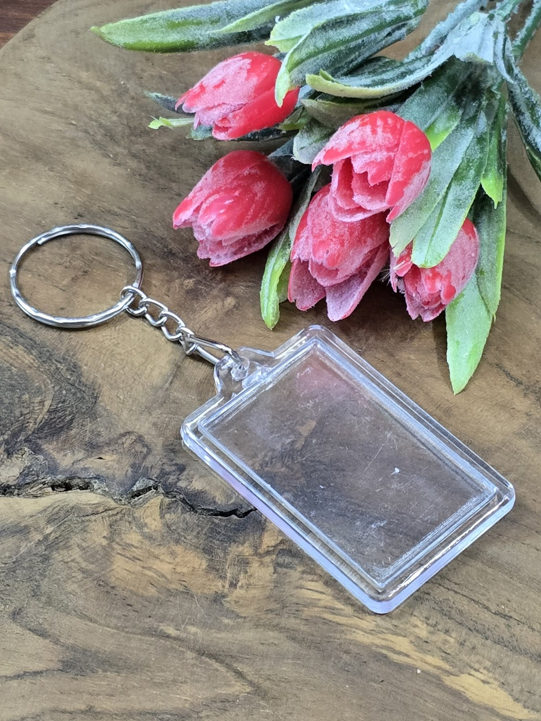 Transparenter rechteckiger Acryl-Schlüsselanhänger für Fotos und kleine Motive vor Blütendekoration.