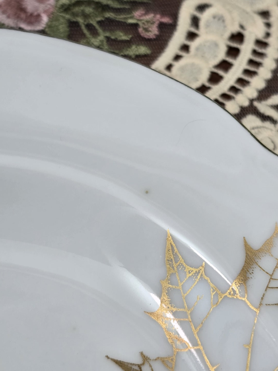 Freiberger Porzellan Servierplatte mit goldenem Blattdekor und kleinem sichtbarem Punkt in der Innenfläche als Detailaufnahme