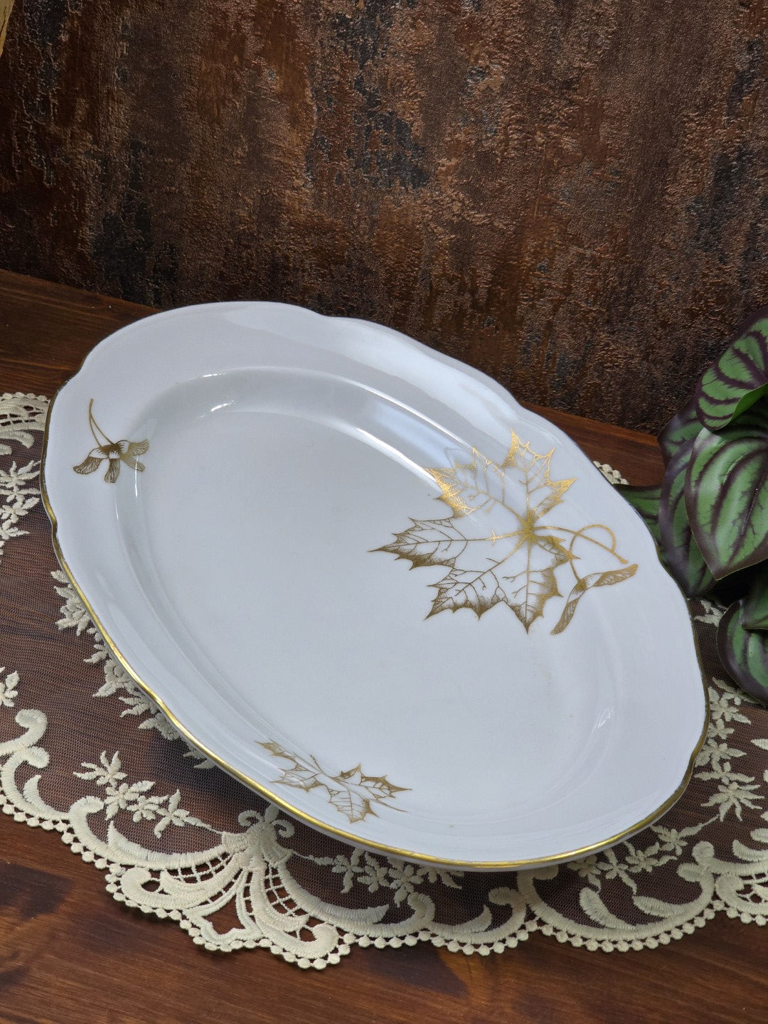 Freiberger Porzellan Servierplatte mit ovaler Form, Goldrand und goldenem Blattdekor schräg von oben fotografiert