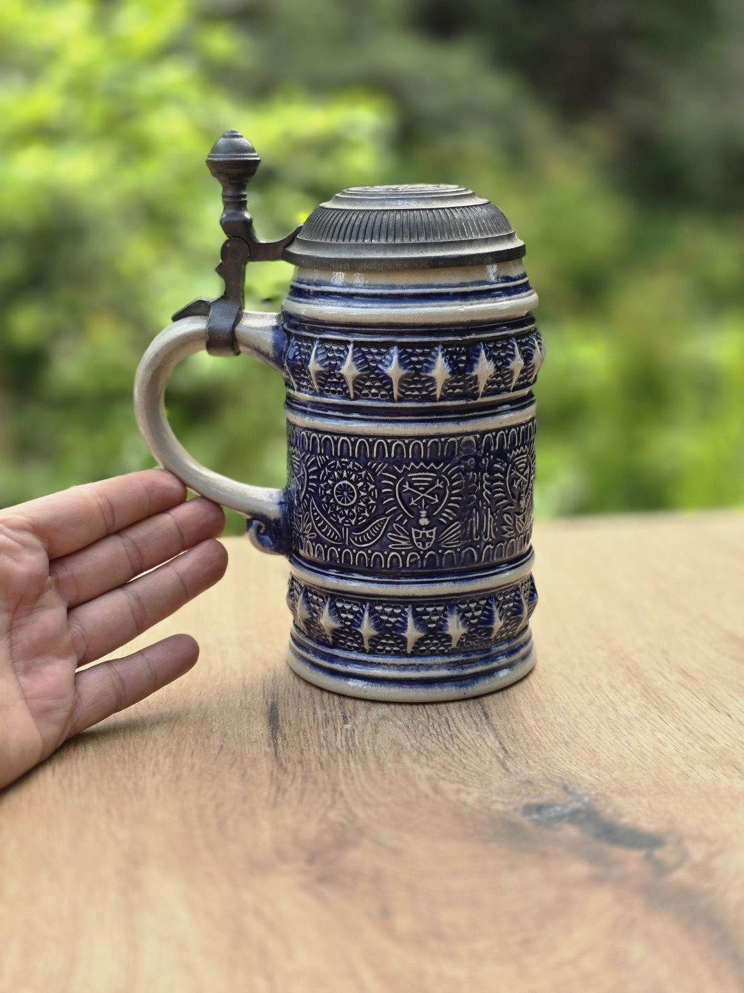 Handgehaltener Steinzeug Bierseidel mit kobaltblauem Dekor und Zinndeckel als Größenvergleich