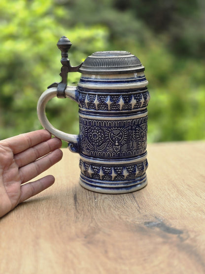 Handgehaltener Steinzeug Bierseidel mit kobaltblauem Dekor und Zinndeckel als Größenvergleich
