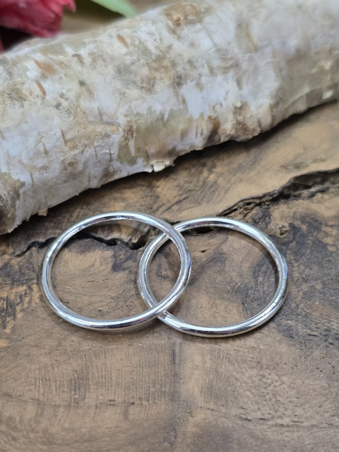 Nahaufnahme von zwei runden, nahtlosen Metallringen in Silberoptik auf dunklem Echtholz zur Detailansicht der glatten Oberfläche.