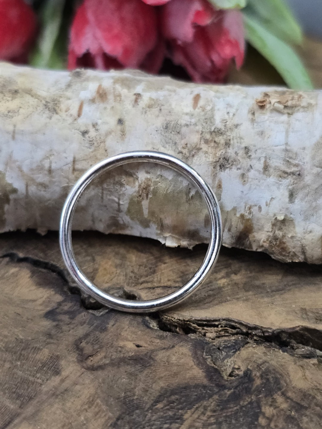 Ein einzelner runder Schmuckring aus Metall (24 mm) hochkant aufgestellt vor einem Birkenstamm als Zubehör für Makramee und Schmuckherstellung.