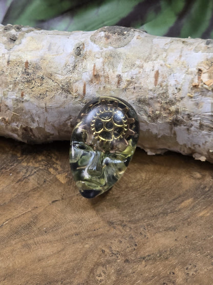Unikat-Cabochon mit geheimnisvollem Gesicht, dunkelgrüner Resin-Optik und metallischen Zahnrädern