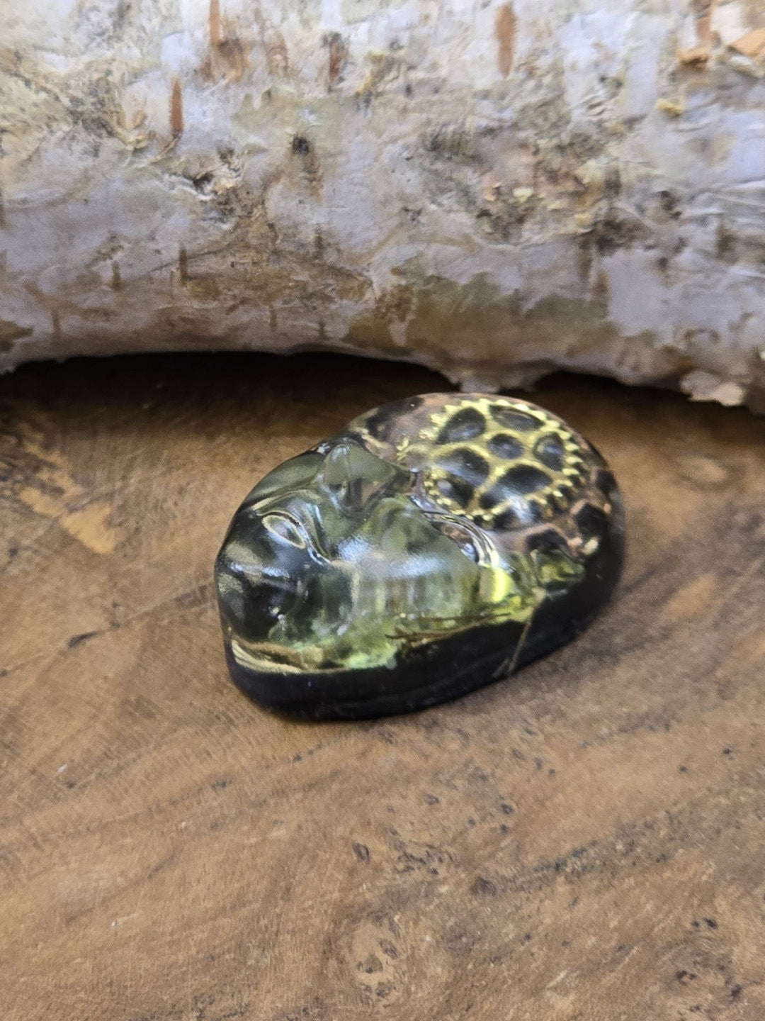 Seitlich liegender Steampunk-Cabochon mit Gesichtsrelief, grünem Resin und goldfarbenen Zahnrädern