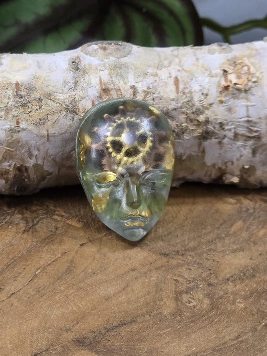 Großer grüner Resin-Cabochon mit Gesichtsmotiv, Zahnrädern und goldfarbenen Steampunk-Details
