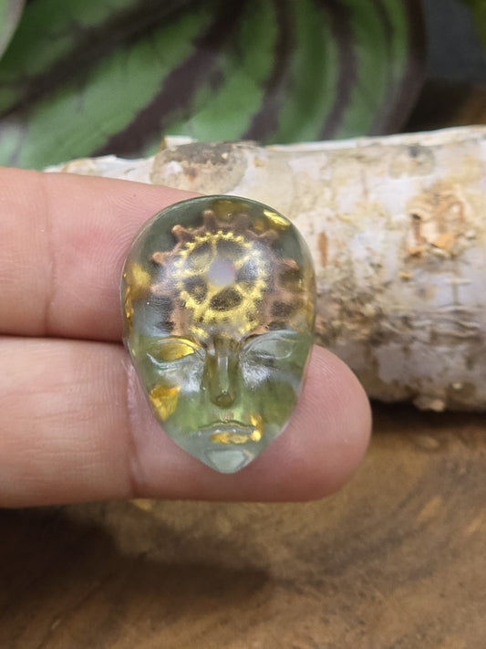 Transparenter Gesicht-Cabochon aus grünem Resin mit eingearbeiteten Zahnrädern zur Größendarstellung