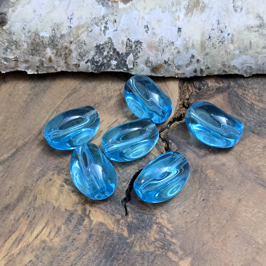 Das Bild zeigt 12 transparente Glasperlen in Nuggetform – Aquablau – 13mm – Für strahlend frische Schmuckkreationen