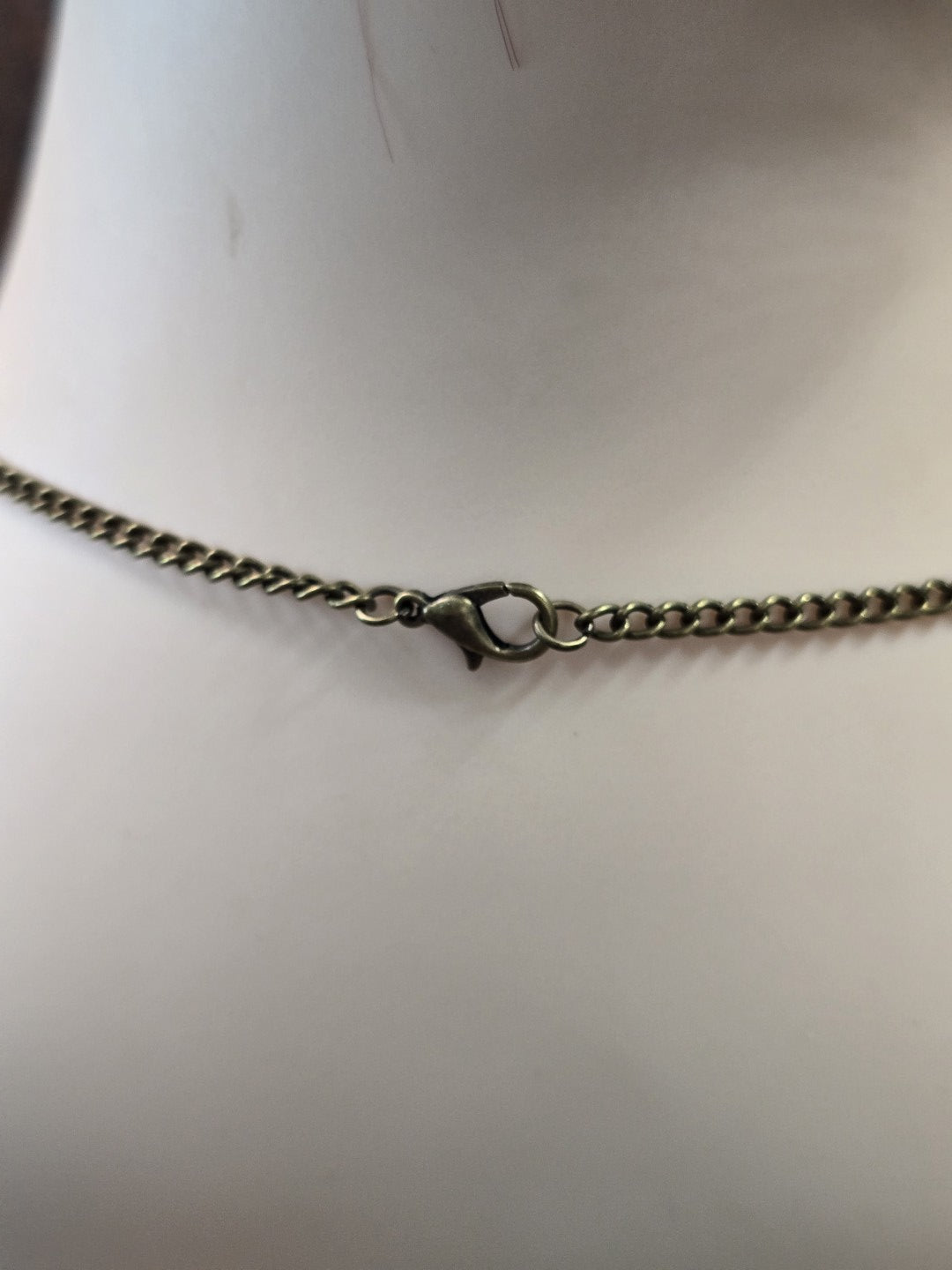 Detailaufnahme des Karabinerverschlusses der bronzefarbenen Metall-Gliederkette.