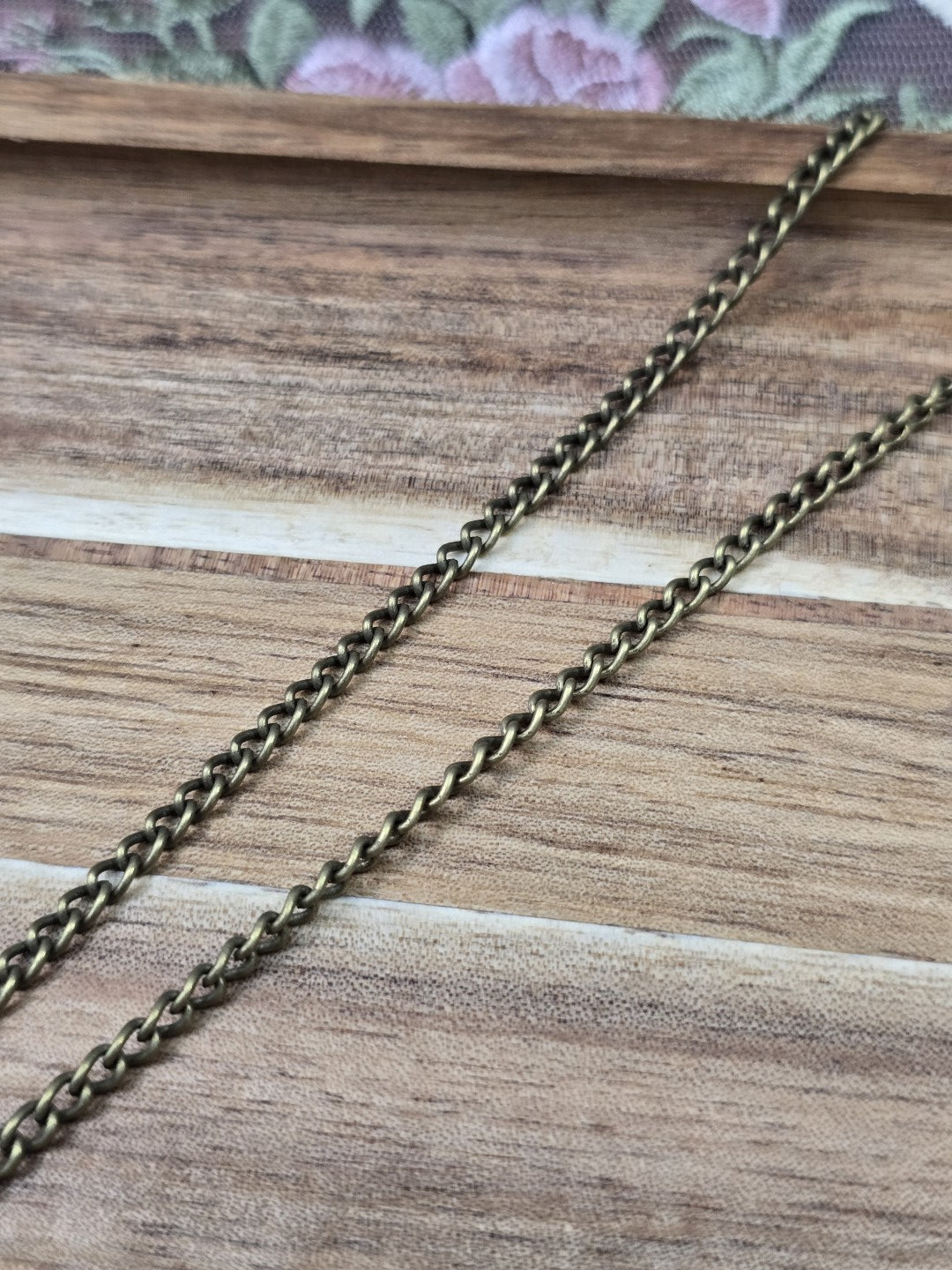 Nahaufnahme der einzelnen Kettenglieder der antiken Bronze-Gliederkette auf Holz.