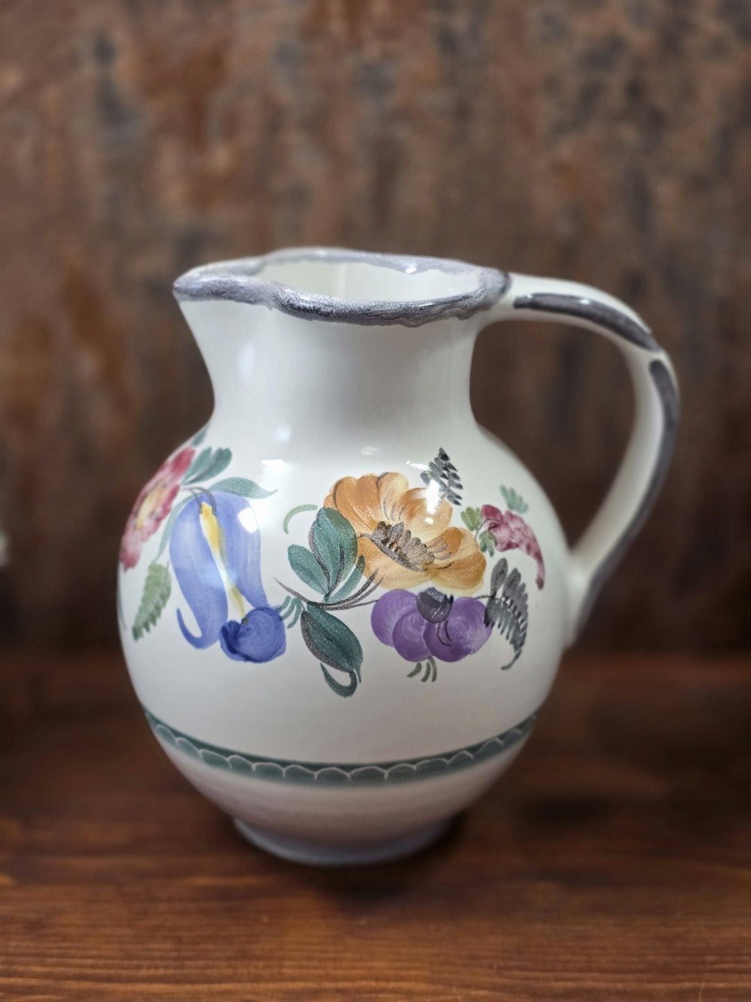 Vintage Keramikkrug mit bauchiger Form, floralem Dekor in Blau, Ocker, Violett und Grün sowie grau gerändertem Ausguss.