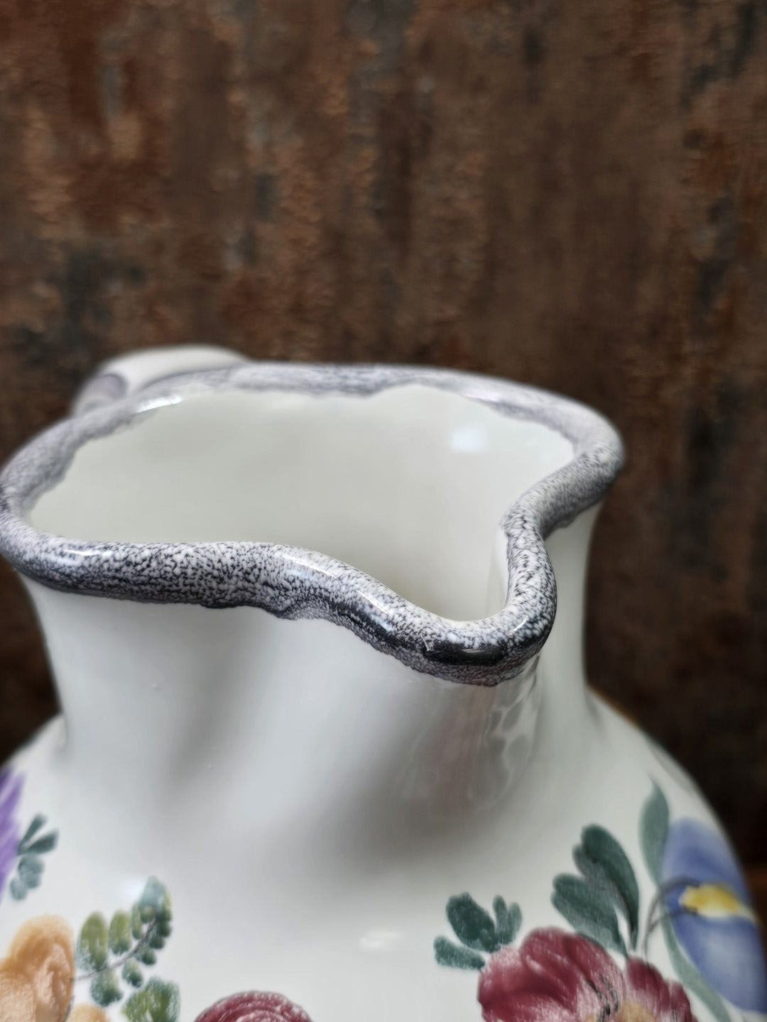 Vintage Keramikkrug mit geschwungenem Ausguss und grau gesprenkeltem Rand, Detailaufnahme von Öffnung und oberem Halsbereich.