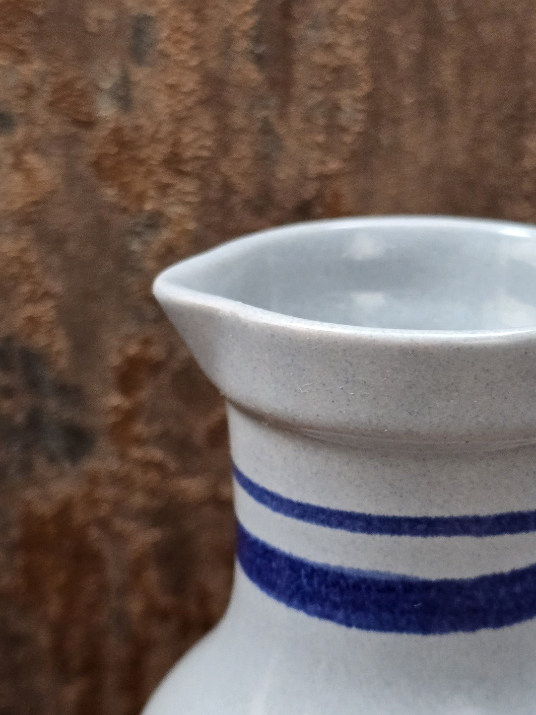 Kleiner Henkelkrug von Gräfenroda aus DDR-Keramik, gestaltet mit blauem Streifenrand und floralem Dekor auf hellem Grund.