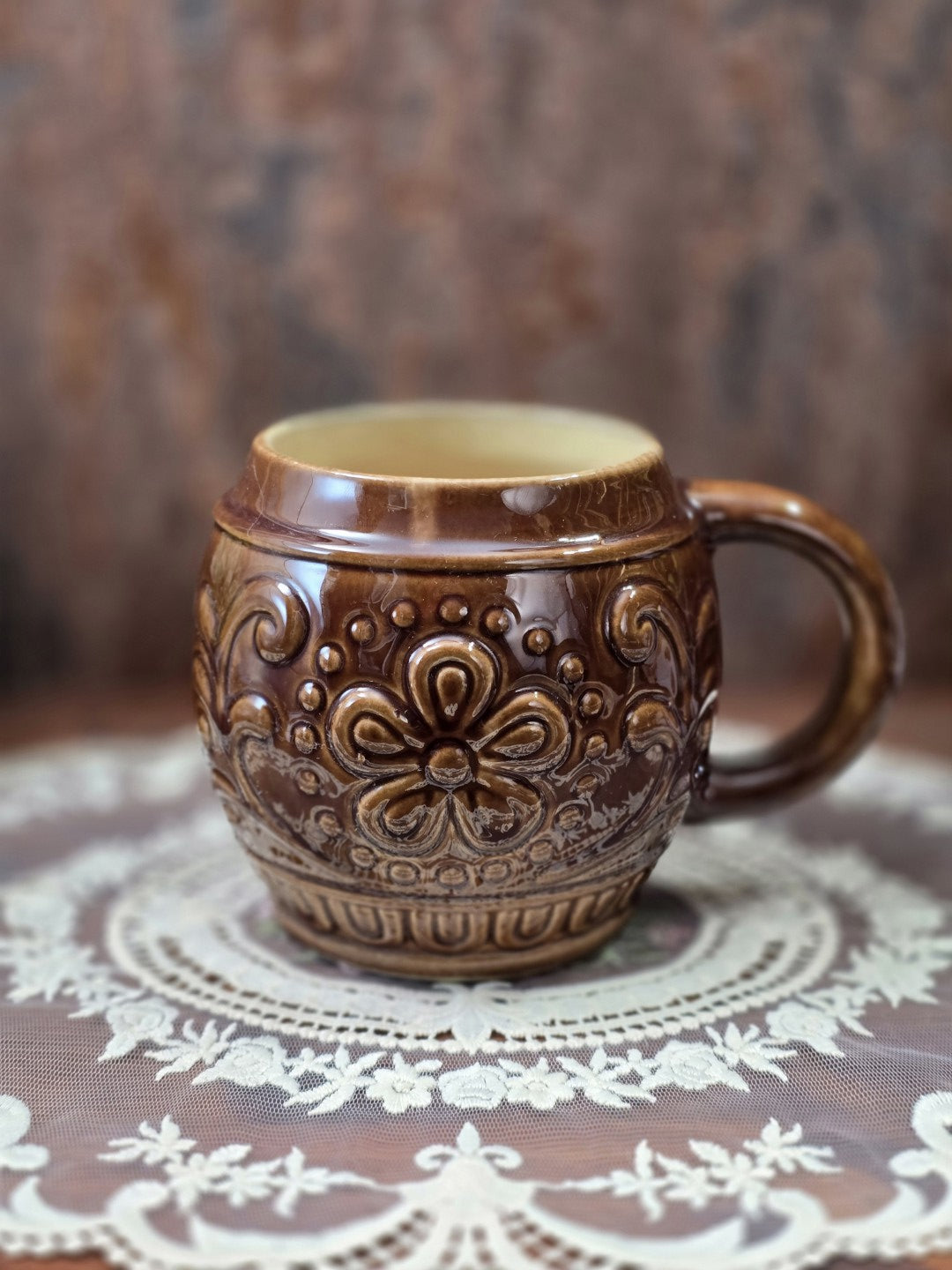 Vintage Keramikbecher von Gräfenroda mit brauner Glasur, floralem Reliefdekor und Henkel auf einer dekorativen Spitzendecke