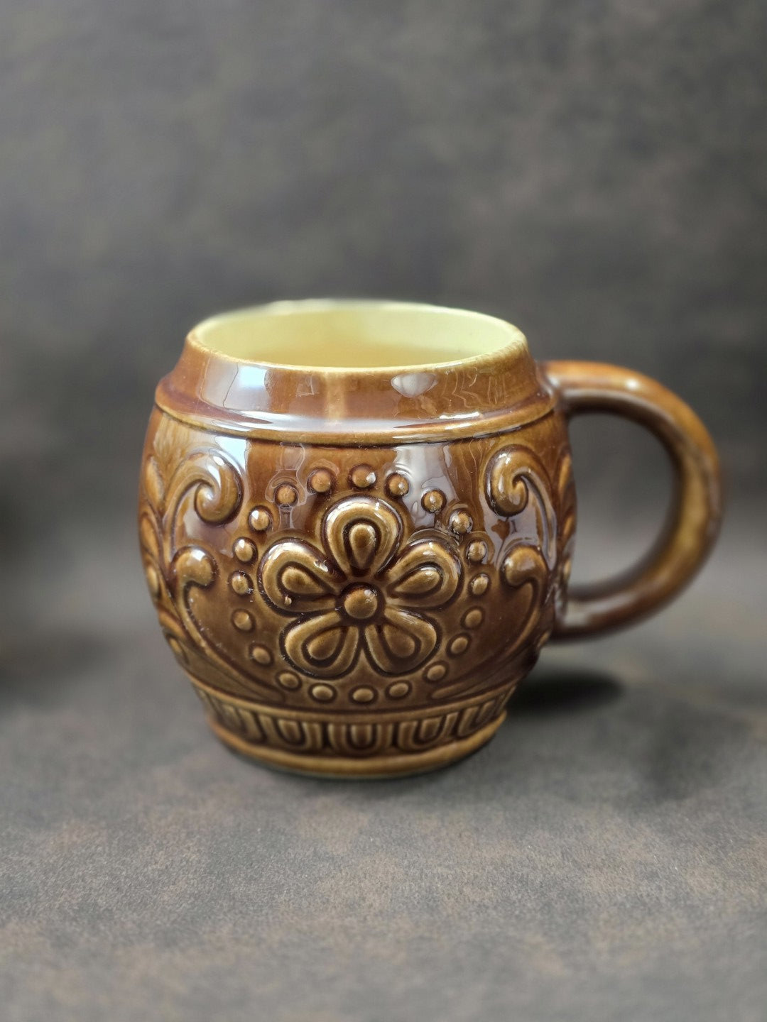 Vintage Keramikbecher von Gräfenroda mit braunem Reliefdekor, cremefarbener Innenfläche und Henkel in schräger Vorderansicht
