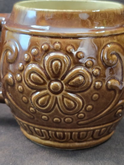 Vintage Keramikbecher mit kräftigem rundem Henkel, brauner Glasur und reliefiertem Dekor in seitlicher Detailansicht