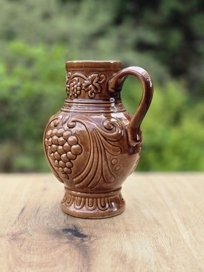 DDR Vintage-Weinkrug von Gräfenroda Keramik mit braunem Keramikkorpus, Weinlaubdekor, Traubenrelief und klassischer runder Krugform.
