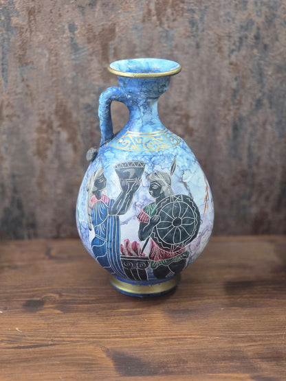 Vintage Keramikkanne in Blau mit Golddekor und zwei schwarz konturierten Figuren mit Gefäß und Rundschild in Rückansicht