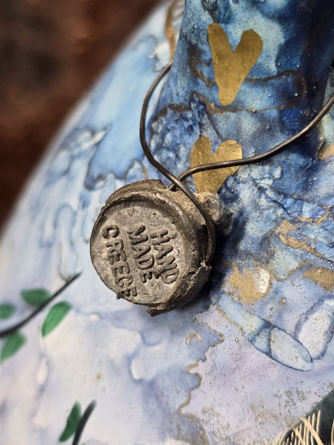 Vintage Keramikkanne mit Metallanhänger am Henkel und sichtbarer Prägung „HAND MADE GREECE“ in Nahaufnahme