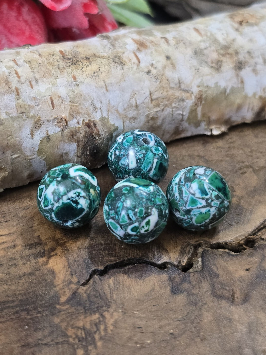 Nahaufnahme von vier grünen Mosaik-Perlen (12 mm) in Kugelform mit markanter Steinmusterung auf Holzgrund.