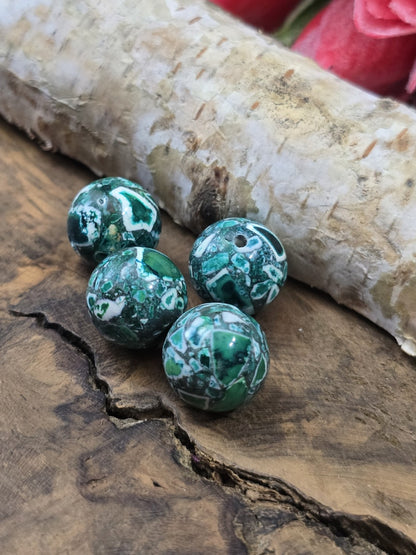 Draufsicht auf vier runde grüne Mosaik-Steinperlen (12 mm) mit sichtbarer Fädelbohrung zur Schmuckgestaltung.
