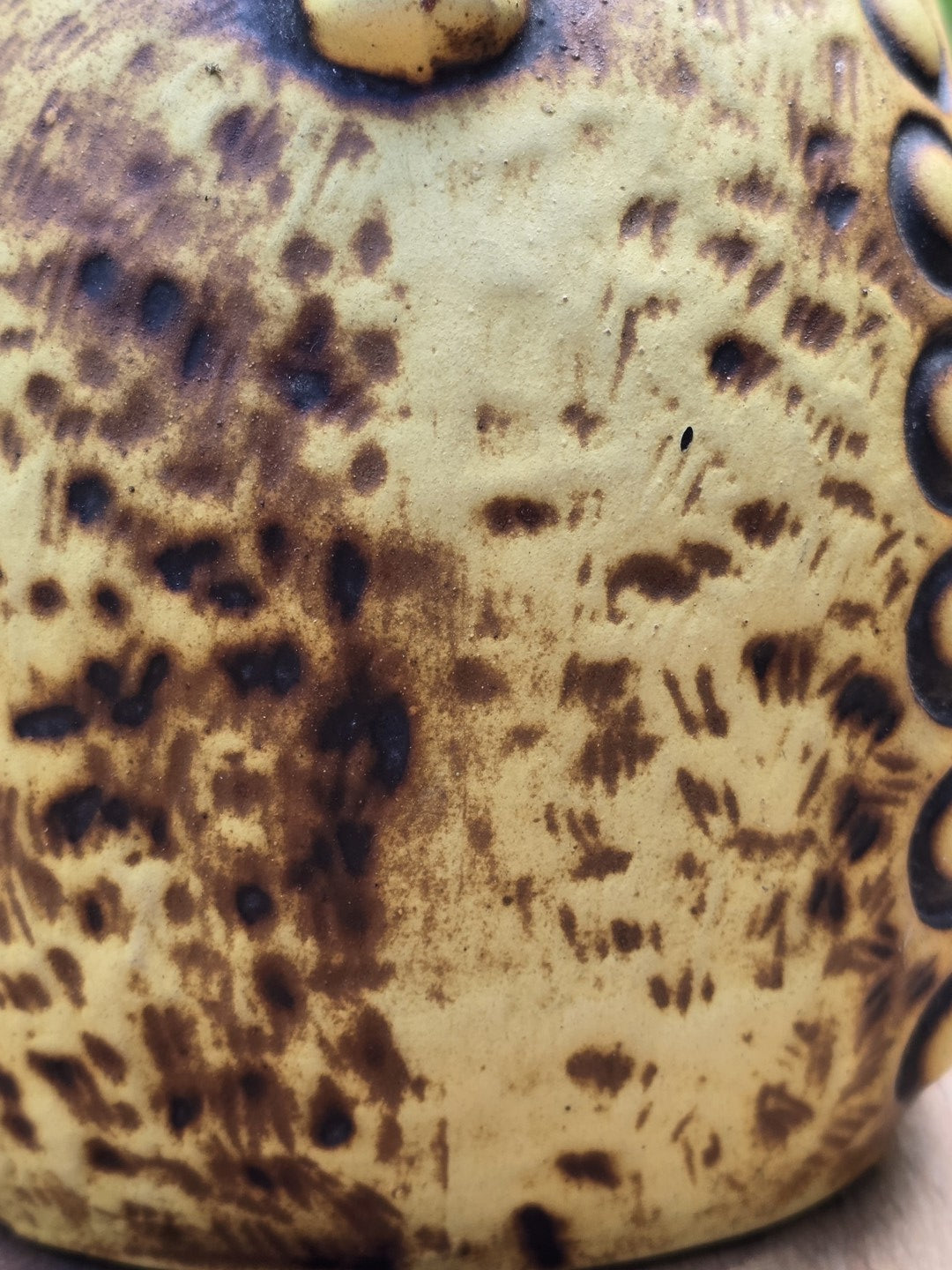 Detail des floralen Reliefdekors am GS Keramik Krug in Senfgelb, Braun und dunklem Blau.