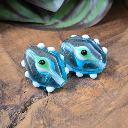 2 handgefertigte Lampwork-Glasperlen in Blau, Oval mit Noppen & Augenmotiv. Einzigartiges Material für kreative Schmuckherstellung.