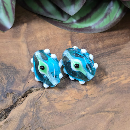 2 handgefertigte Lampwork-Glasperlen in Blau, Oval mit Noppen & Augenmotiv. Einzigartiges Material für kreative Schmuckherstellung.