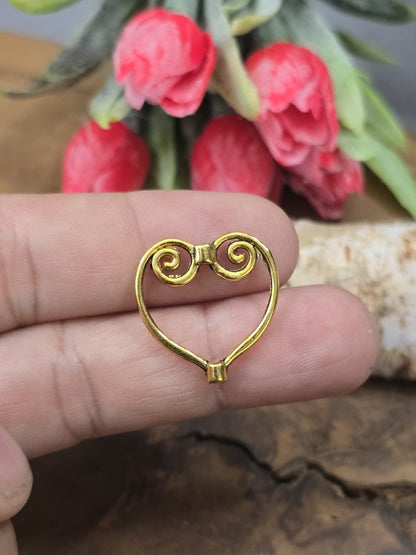 Ein goldener Herz-Perlenrahmen auf einer Fingerkuppe präsentiert als Größenvergleich für DIY-Schmuckprojekte.
