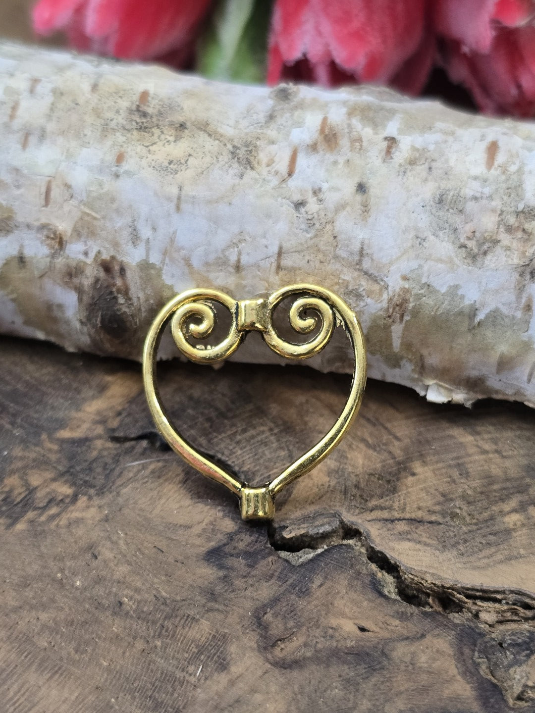 Ein einzelner goldfarbener Herz-Perlenrahmen (21 mm) hochkant aufgestellt vor Birkenrinde auf einer rustikalen Holzscheibe.